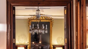 Ein beeindruckender Eingangsbereich mit einer Chandelier, einem Spiegel und einem Essbereich mit Tisch und Stühlen.