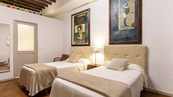 Quarto de hotel com duas camas, teto de madeira e obras de arte nas paredes.
