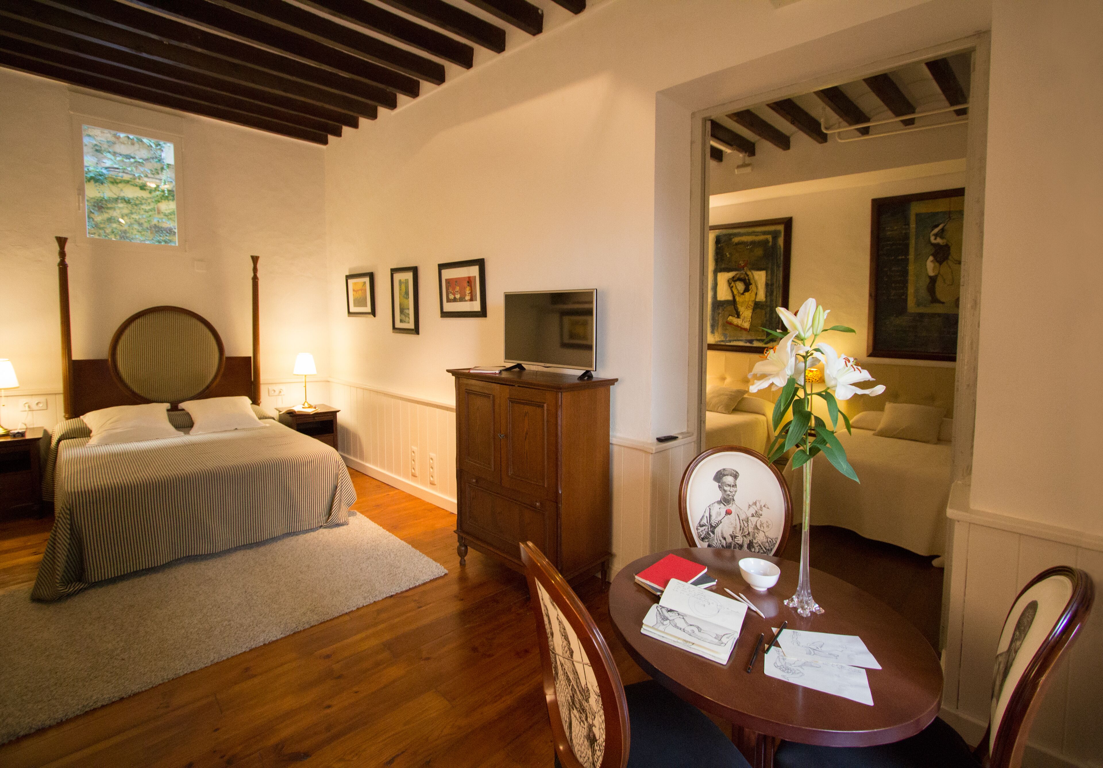 Un dormitorio con una cama, un tocador, un escritorio con papeles y una silla.