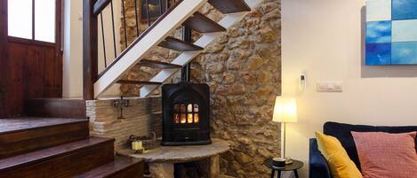 A staircase leading to a stone wall with a fireplace, a blue couch with cushions, and a painting on the wall.