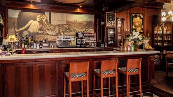 Un bar con taburetes de madera, un espejo grande y una variedad de botellas y vasos.