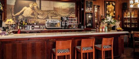 Un bar con taburetes de madera, un espejo grande y una variedad de botellas y vasos.