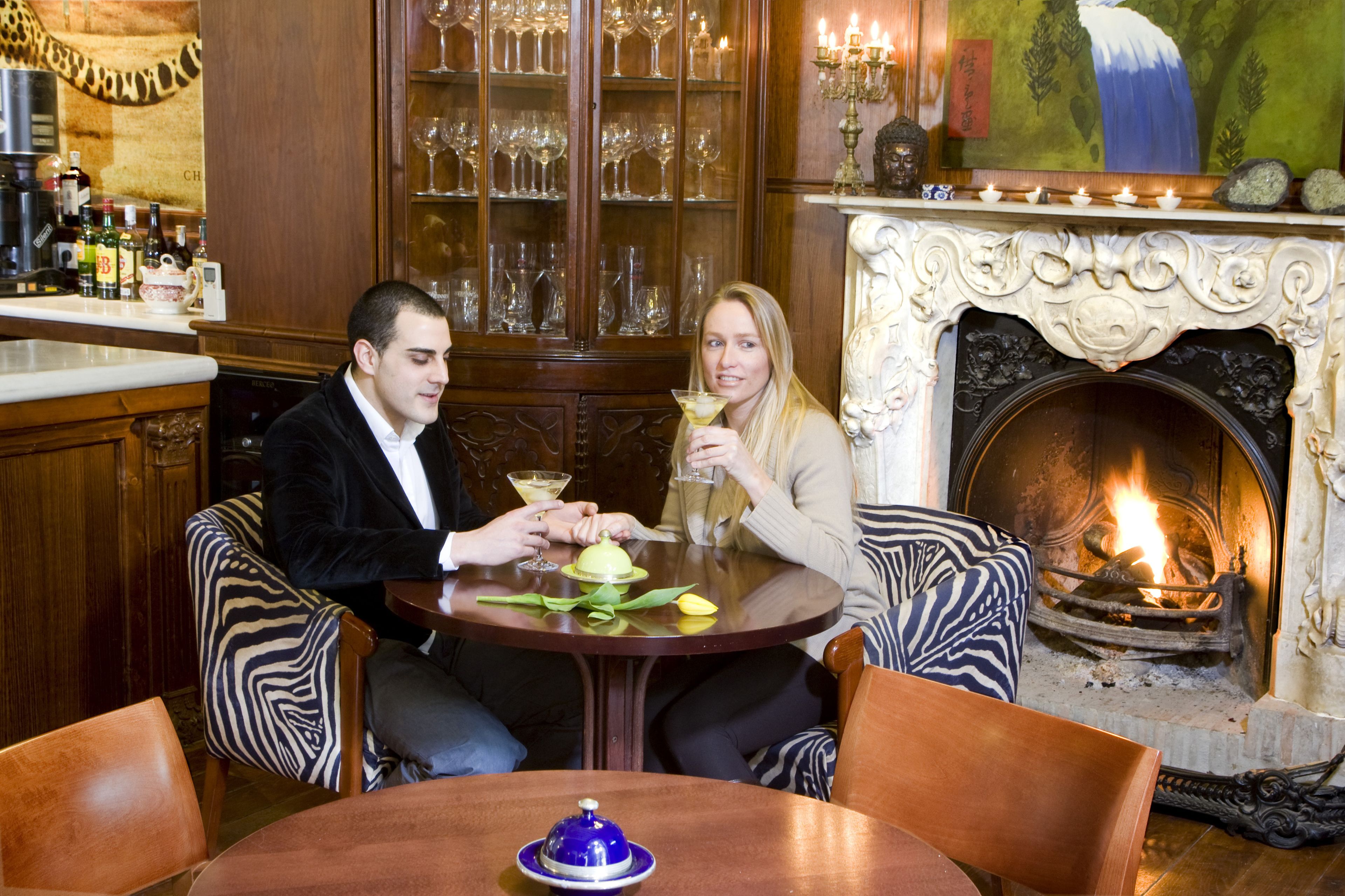 A couple seated at a round table with a fireplace in the background.
