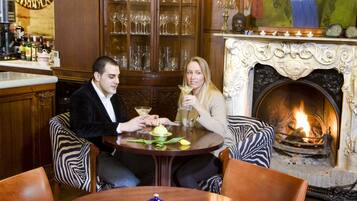 A couple seated at a round table with a fireplace in the background.