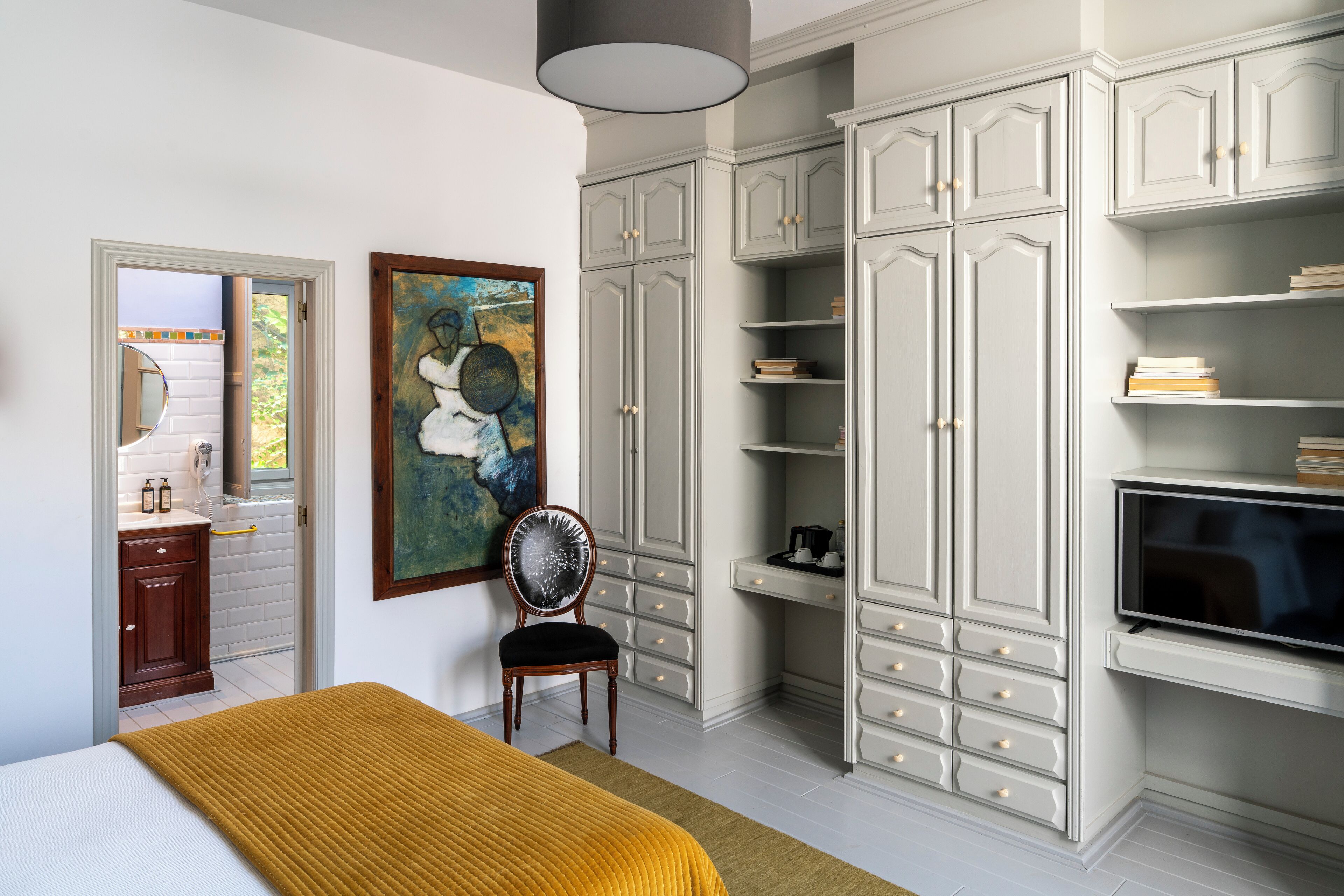A bedroom with a bed, a chair, a wardrobe, and a television.