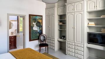 Un dormitorio con cama, una silla, armario y televisor.
