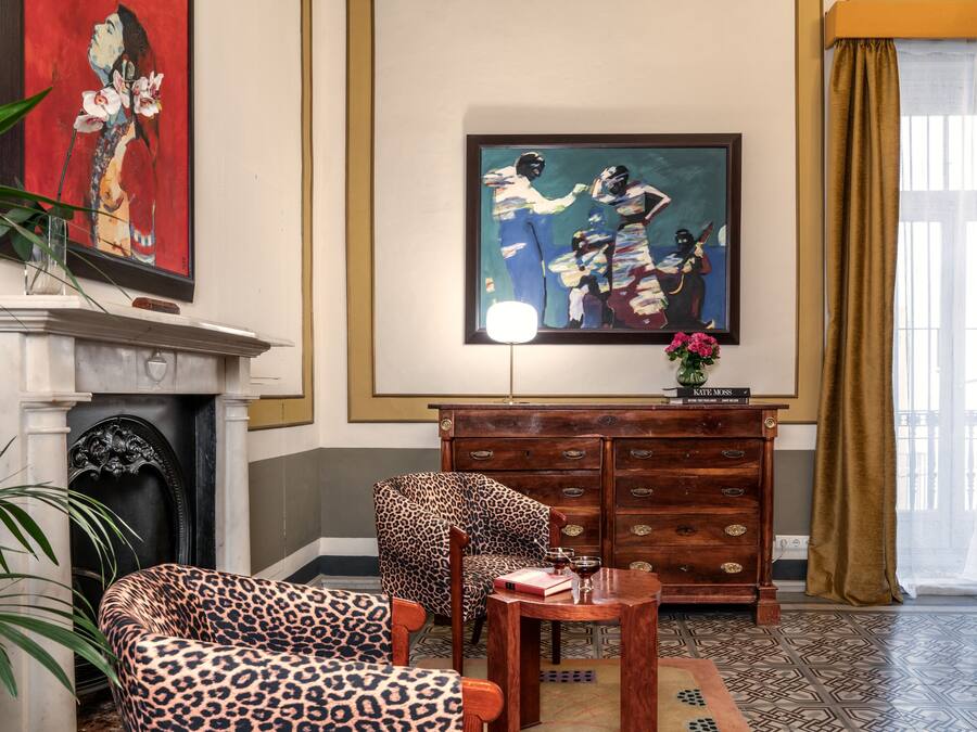 A room with a fireplace, a leopard-print armchair, a wooden cabinet, and a painting on the wall.