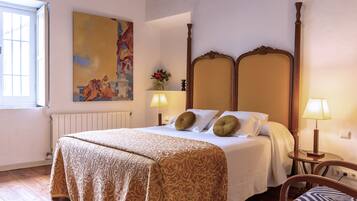 A hotel room with a large bed, a wooden headboard, a painting on the wall, a window, and a chair.