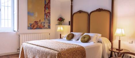 A hotel room with a large bed, a wooden headboard, a painting on the wall, a window, and a chair.
