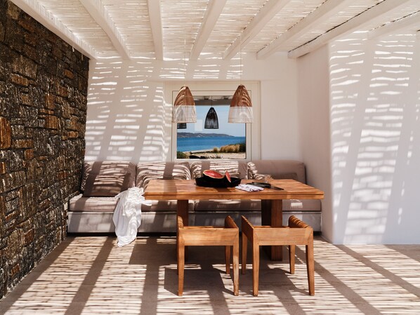 A cozy room with a stone wall, a wooden table, and a view of the sea.