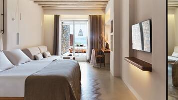 Habitación de hotel moderna con una cama grande, un escritorio y vista al mar a través de un ventanal.