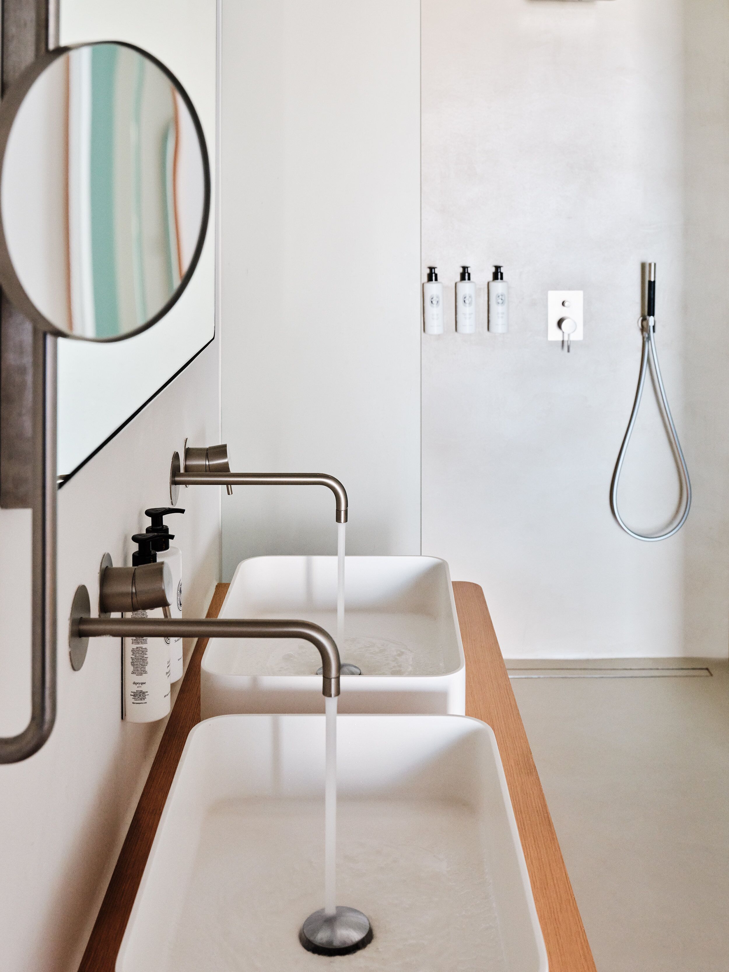 A modern bathroom with two sinks, a mirror, and a shower.