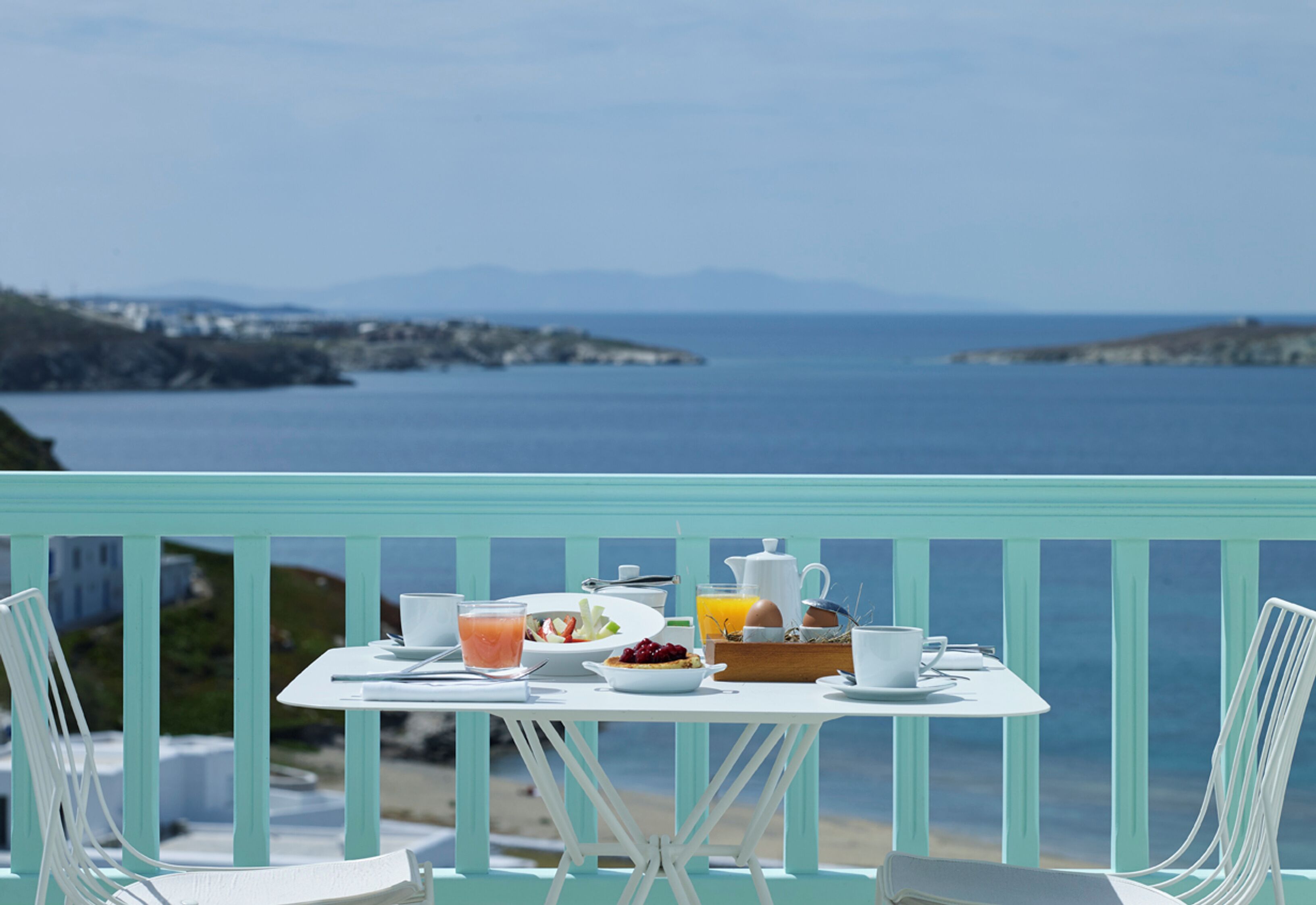 A table set with breakfast items and a view of the sea.