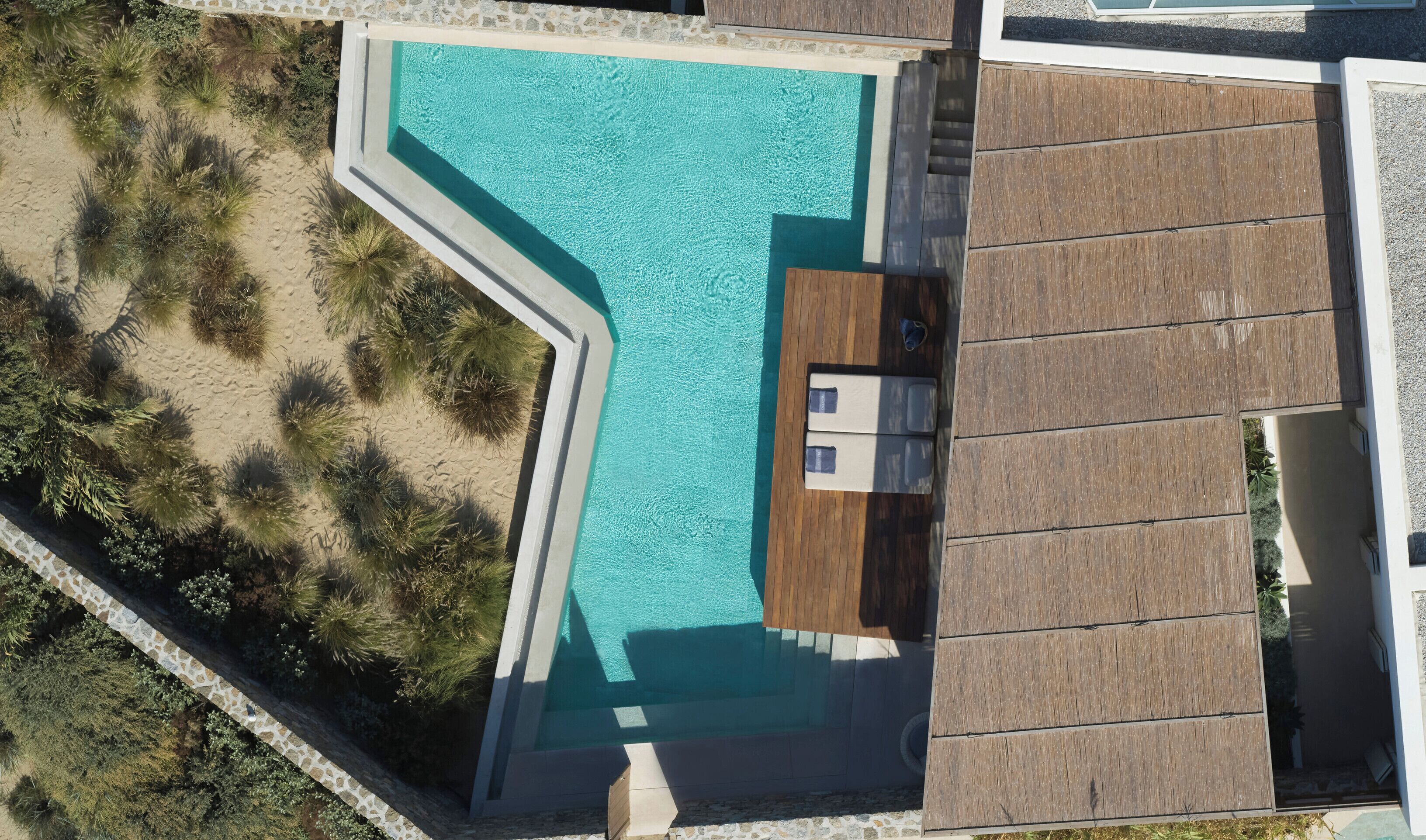 Vista aérea de una piscina con cubierta de madera y un pequeño edificio junto a ella.