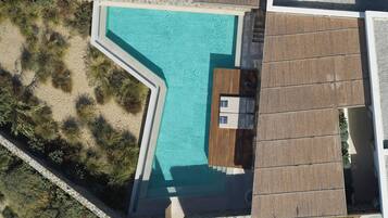 Vista aérea de una piscina con cubierta de madera y un pequeño edificio junto a ella.