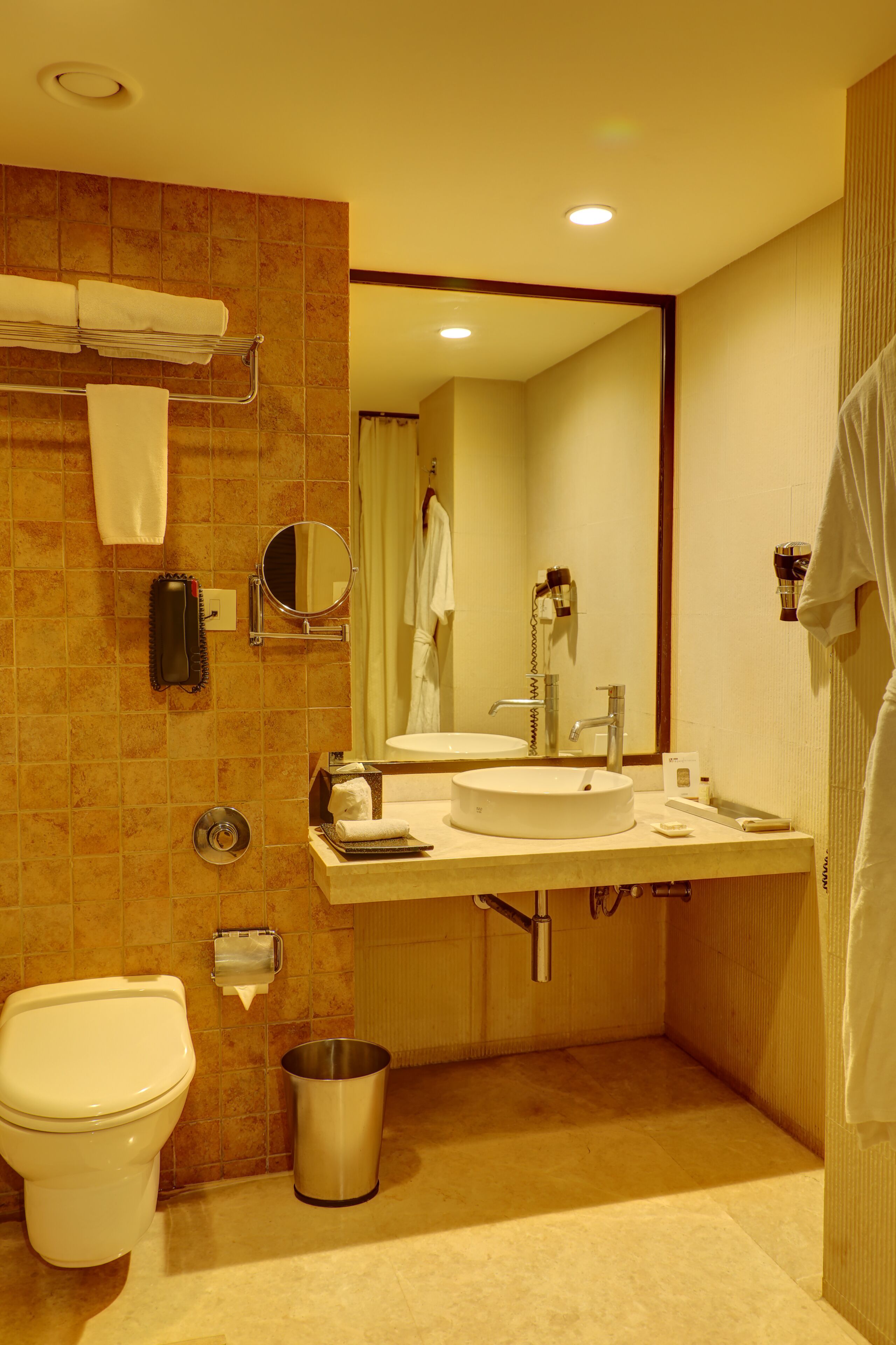 A bathroom with a toilet, sink, mirror, and towel rack.