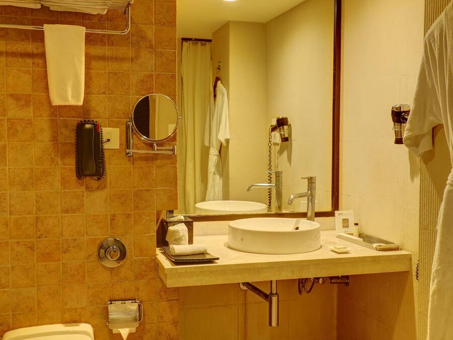 A bathroom with a toilet, sink, mirror, and towel rack.