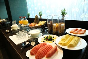 Un ricco buffet della colazione con frutta, verdura e bevande assortite.