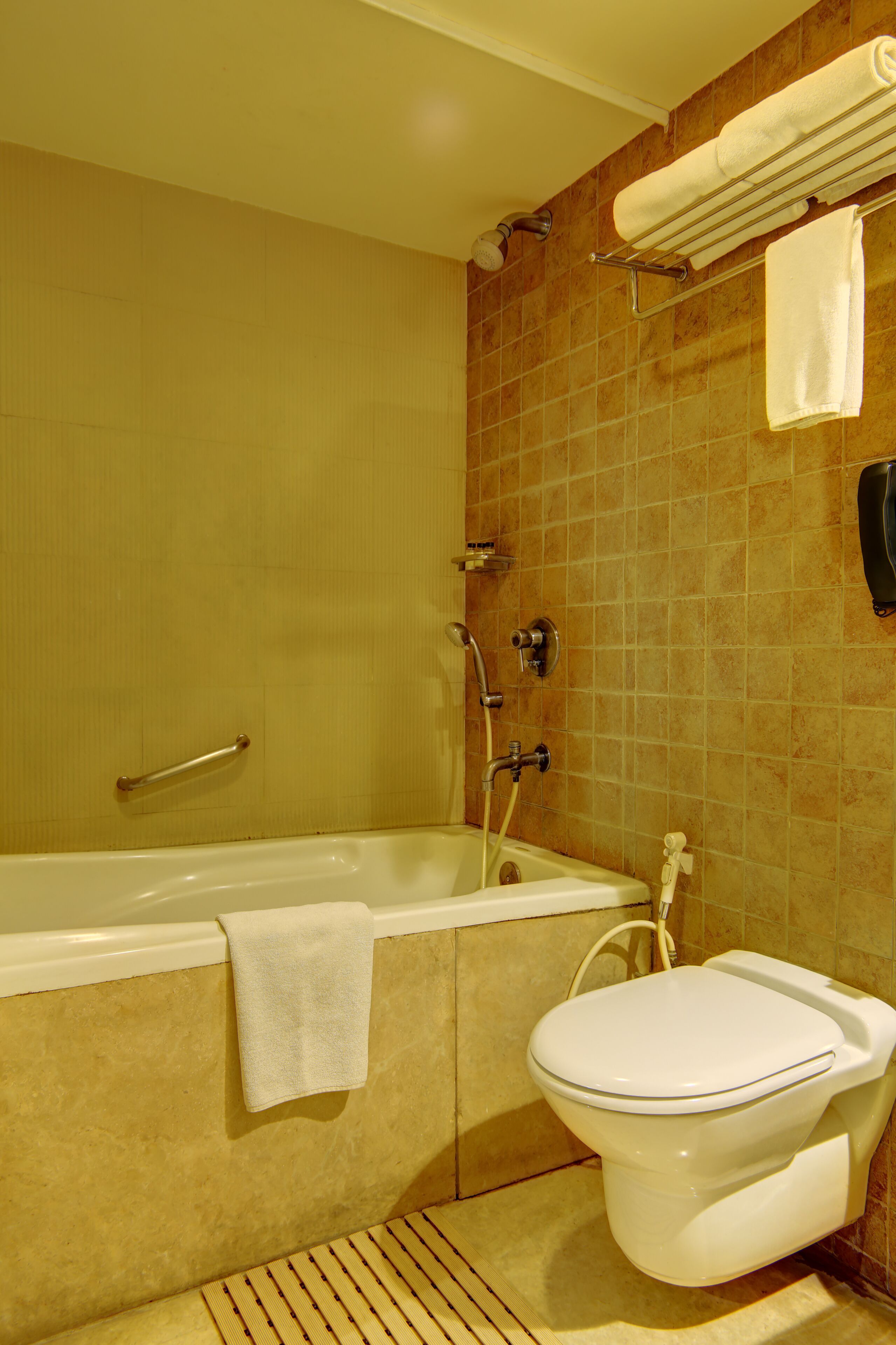A bathroom with a bathtub, toilet, and a towel rack.