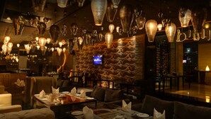 A restaurant interior with multiple dining tables, chairs, and hanging light fixtures. - Mosaic Original, Noida (Noida)