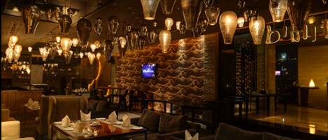 Interior de restaurant amb diverses taules, cadirees i llums penjants.