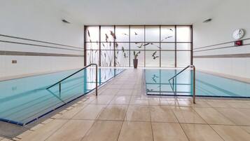 A swimming pool area with glass railings, tiled floors, and decorative panels with bird silhouettes.