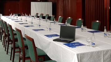 A conference room with a long table, chairs, a laptop, water bottles, and name cards.