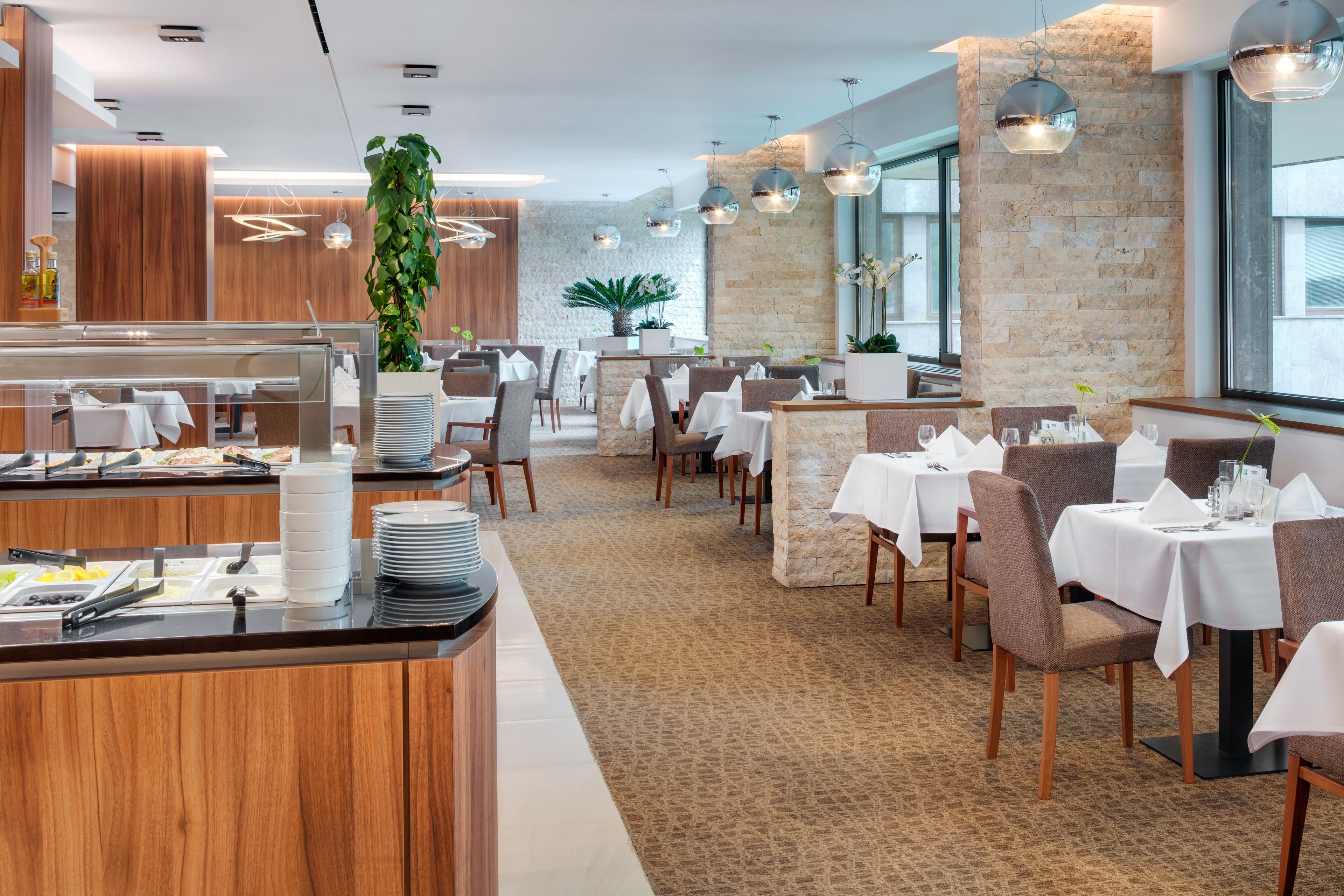 Un restaurante moderno con paneles de madera, paredes de piedra y una zona de bufé.
