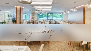 Een modern restaurantinterieur met een centrale tafel waarop het woord 'gallery' in elegante letters staat.