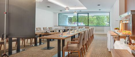 A conference room with long tables, chairs, a projector, and a buffet area.