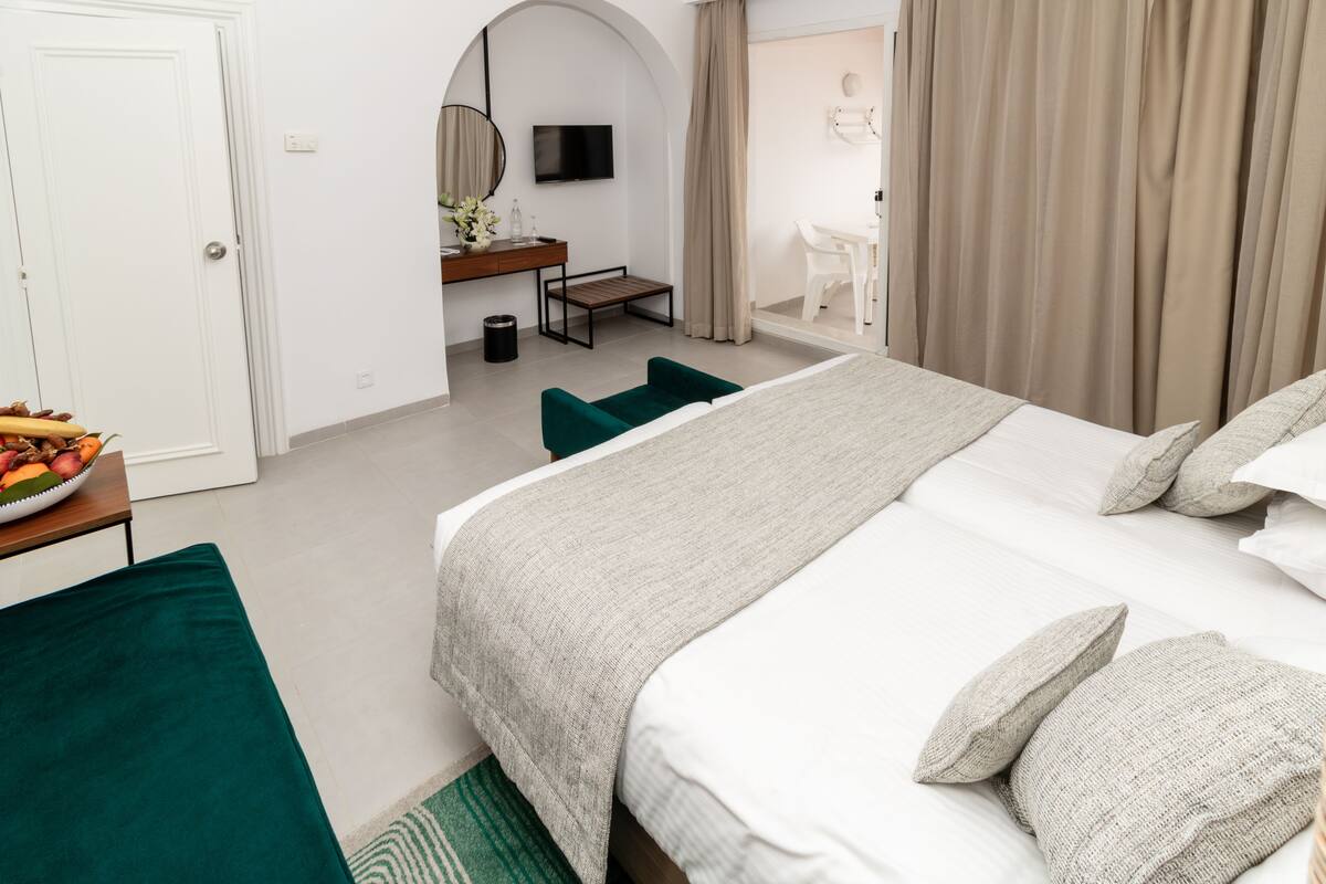 A hotel room with a bed, a desk, a chair, and a television.