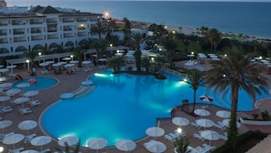 A resort with a large swimming pool, sun loungers, umbrellas, and a view of the ocean. - El Mouradi Palm Marina (Port El Kantaoui)