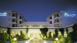 A hotel with a central courtyard, illuminated signage, and a fountain. - El Mouradi Palm Marina (Port El Kantaoui)