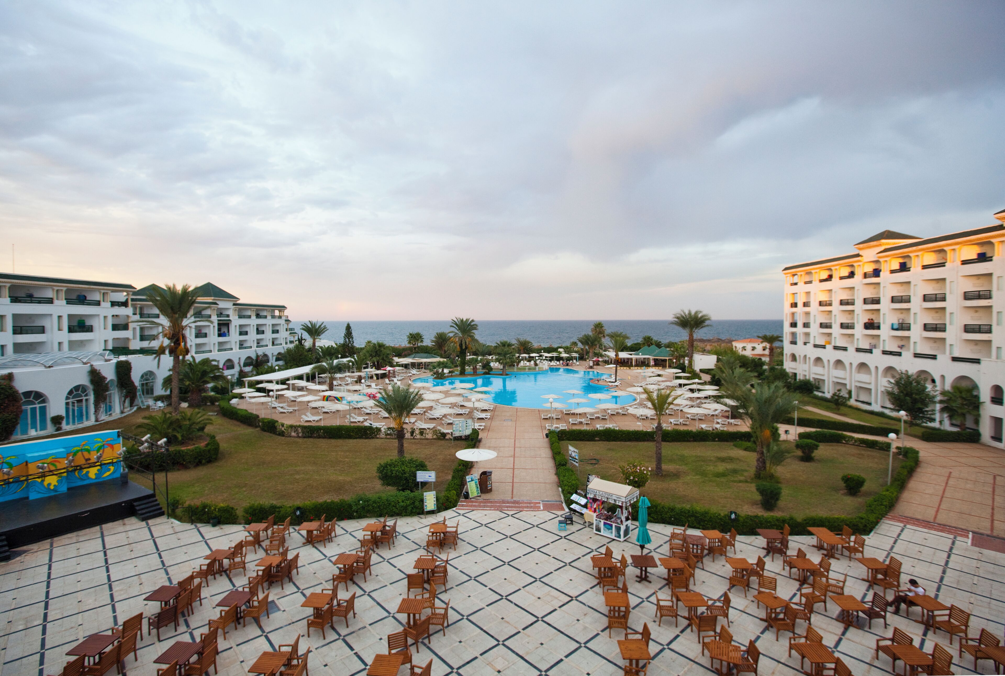 A hotel with a swimming pool, outdoor seating, and a view of the sea.