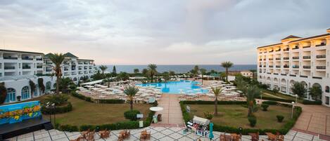 A hotel with a swimming pool, outdoor seating, and a view of the sea.