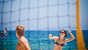 A beach volleyball game with a net and players in the foreground. - El Mouradi Club El Kantaoui (Port El Kantaoui)