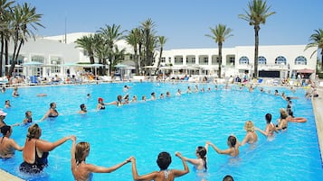 Relax by the spacious pool surrounded by palm trees and sun loungers, perfect for a leisurely day.