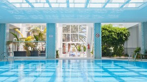 An indoor swimming pool with clear glass ceilings, tiled walls, and potted plants. - El Mouradi Club El Kantaoui (Port El Kantaoui)