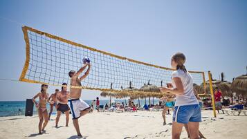 A beach volleyball game with players and spectators.