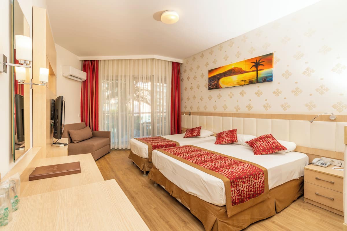 A hotel room with two beds, a sofa, a TV, and a painting on the wall.