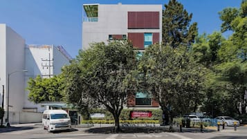 Um edifício moderno com fachada branca, grandes janelas e uma placa vermelha que indica um hotel.