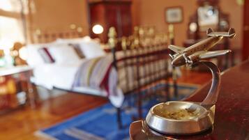 A room with a bed, a metal airplane decoration, and a small metal bowl on a stand.