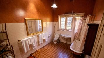 Un baño con piso a cuadros, paredes de azulejos blancos, piso de madera, lavamanos blanco, inodoro y bañera.