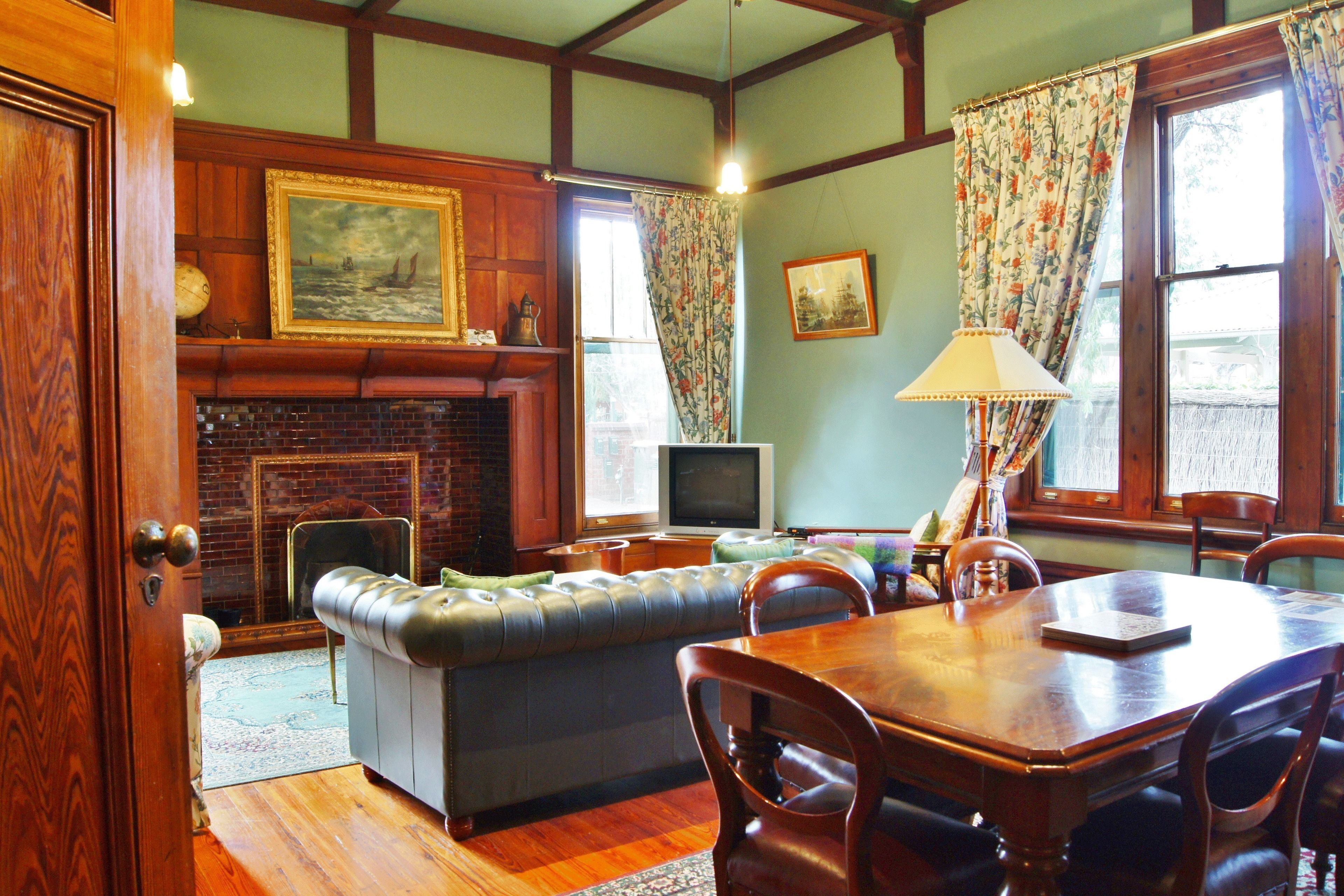 A cozy living room with a fireplace, a television, a sofa, and a dining table with chairs.