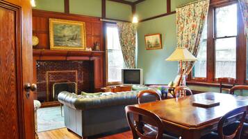 A cozy living room with a fireplace, a television, a sofa, and a dining table with chairs.