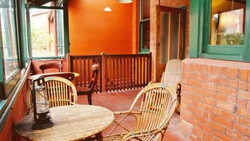 A wicker table and chairs on a balcony with brick walls and a wooden railing.