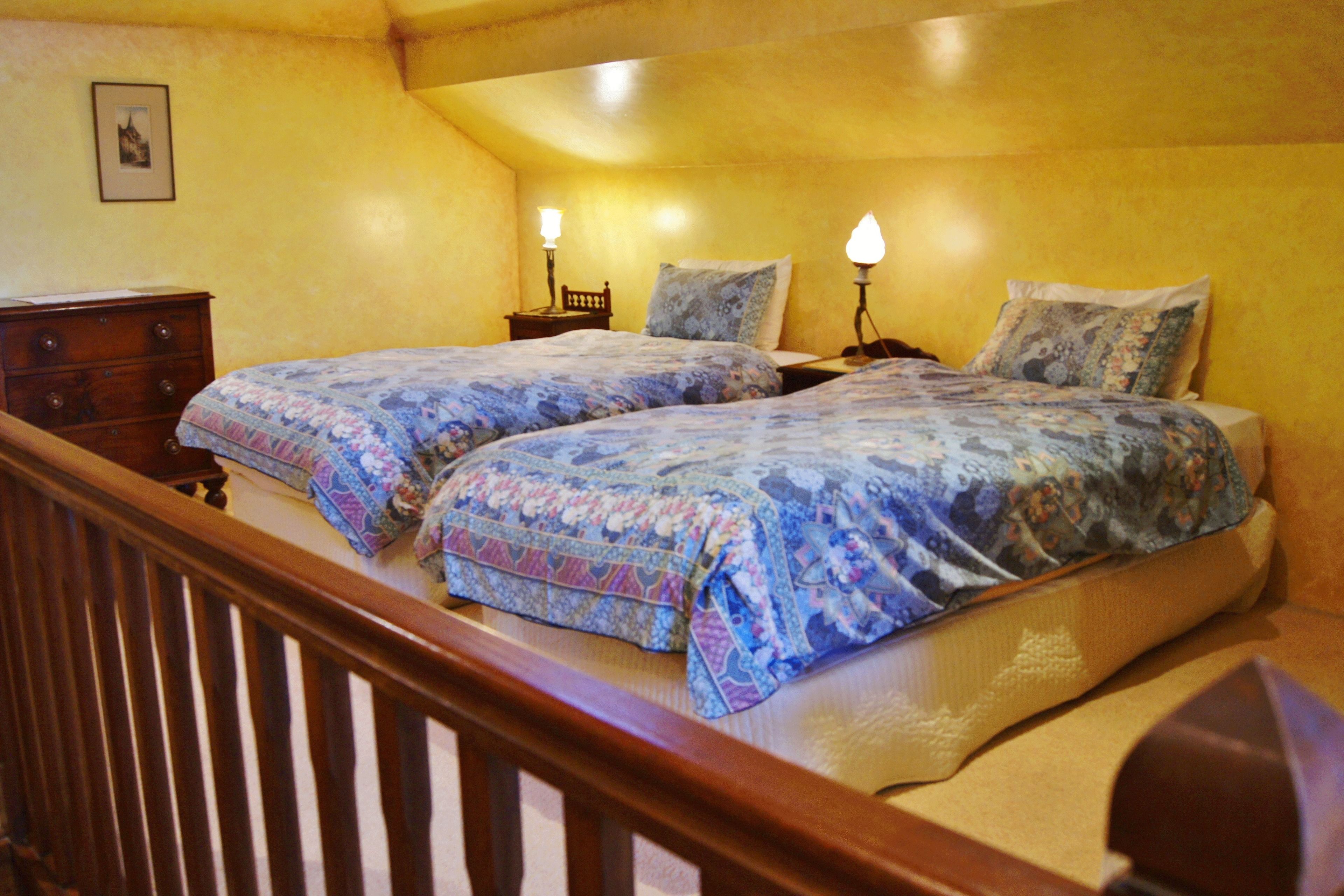 A bedroom with two beds, wooden headboards, and bedside lamps.