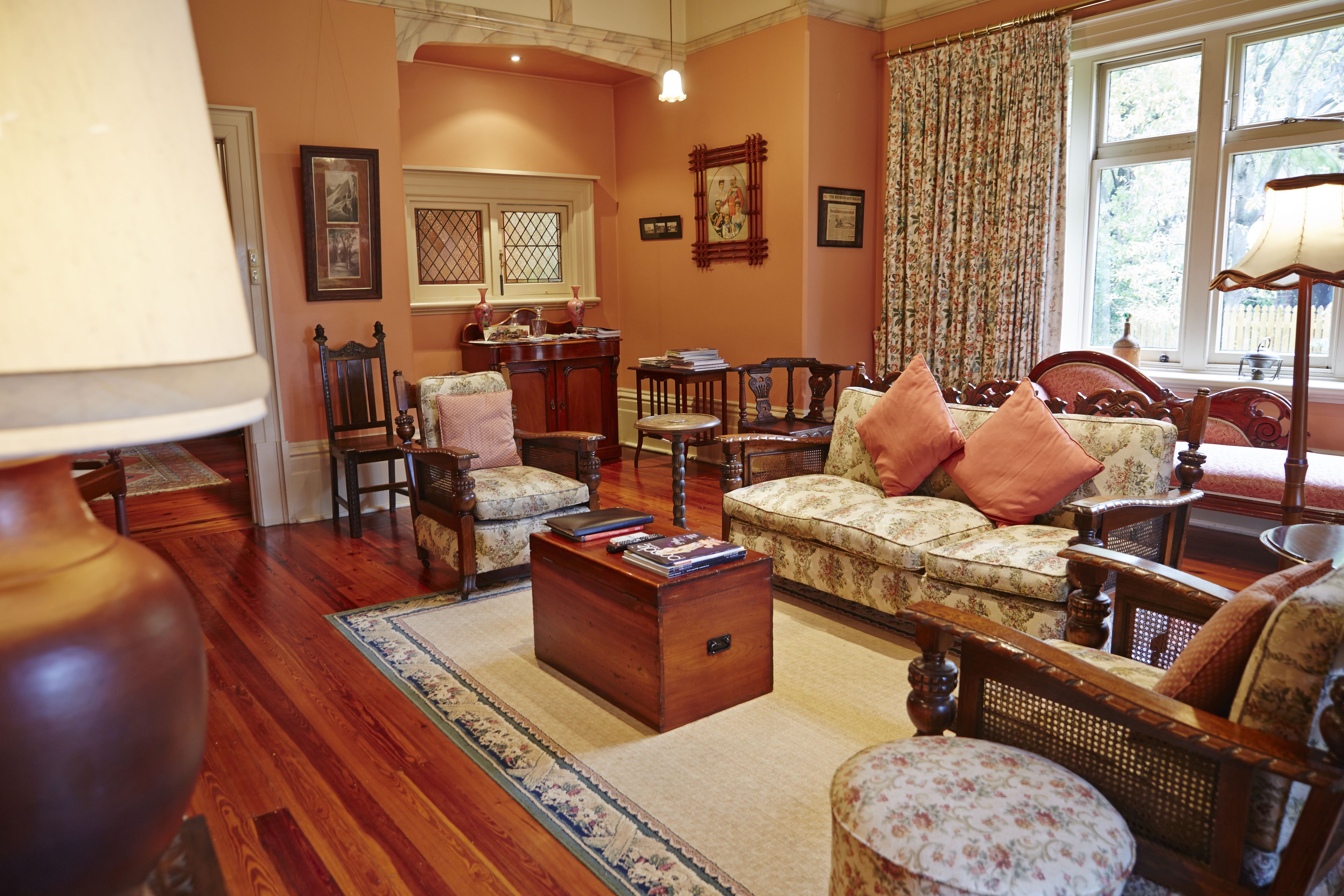 Un salón tradicional con un sofá, sillones, una mesa de centro de madera y una alfombra estampada.