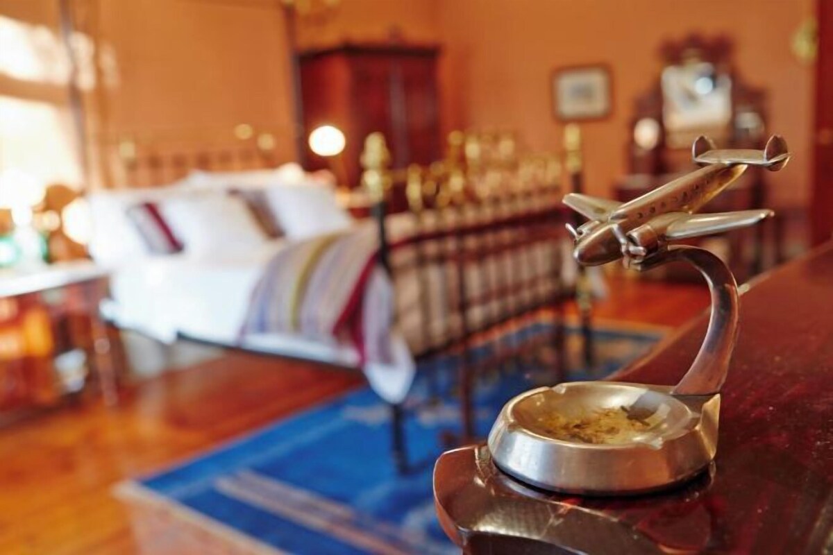 Una habitación con una cama, una mesita con un cuenco y un avión decorativo.