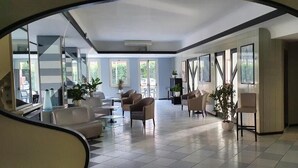 A spacious living area with a high ceiling, large windows, and a modern interior design.